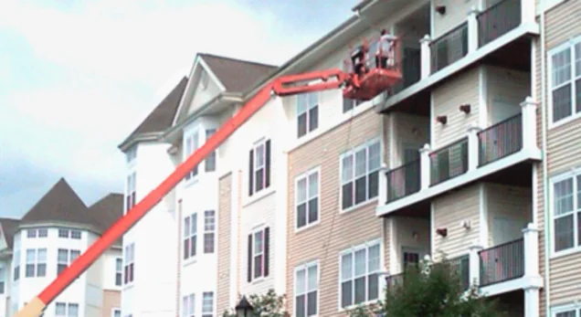 Crew washing a four-story apartment building from a lift
